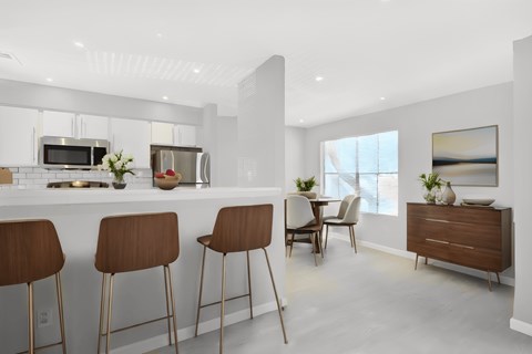 an open kitchen and dining area with bar stools and a table with chairs